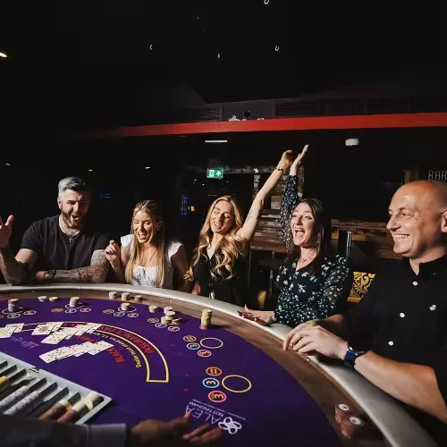 Focused woman engaged with laptop, surrounded by vibrant neon roulette wheels and glowing slot symbols in futuristic casino atmosphere